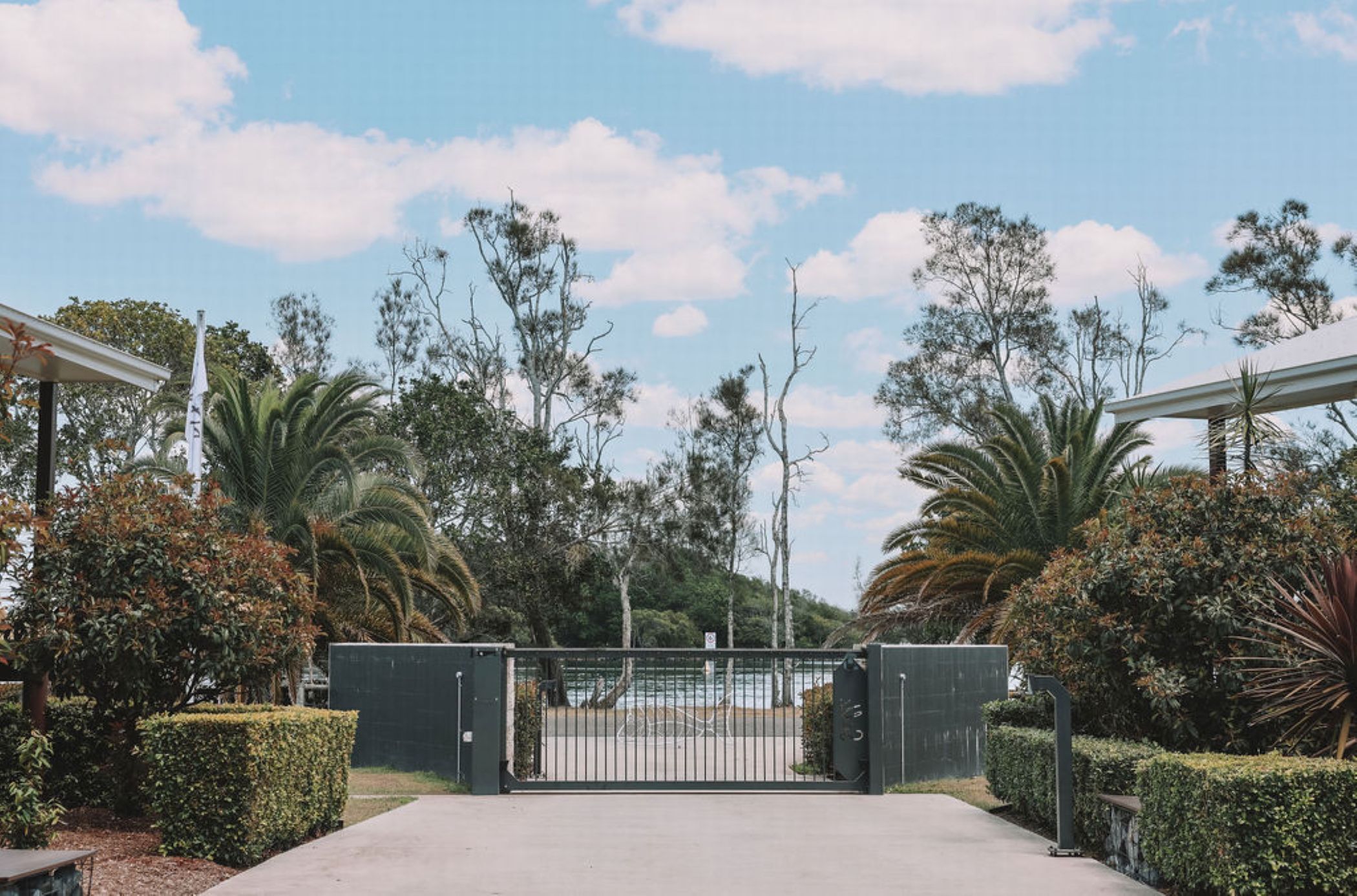A gated entrance with a pathway leading to a building, surrounded by lush greenery and trees.