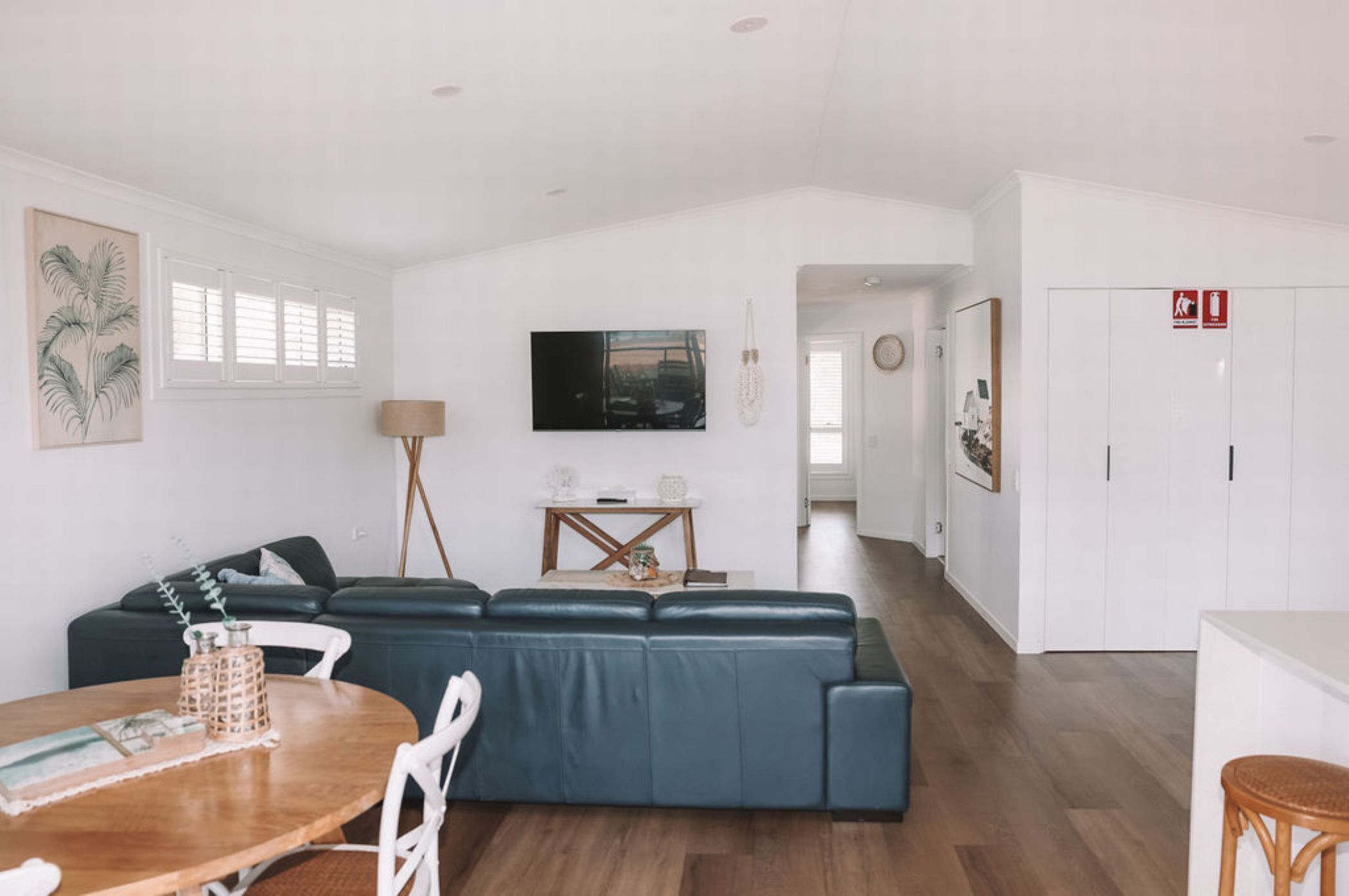 A modern living room with a dark blue sectional sofa, a wooden dining table with chairs, and a small side table with decorative items.