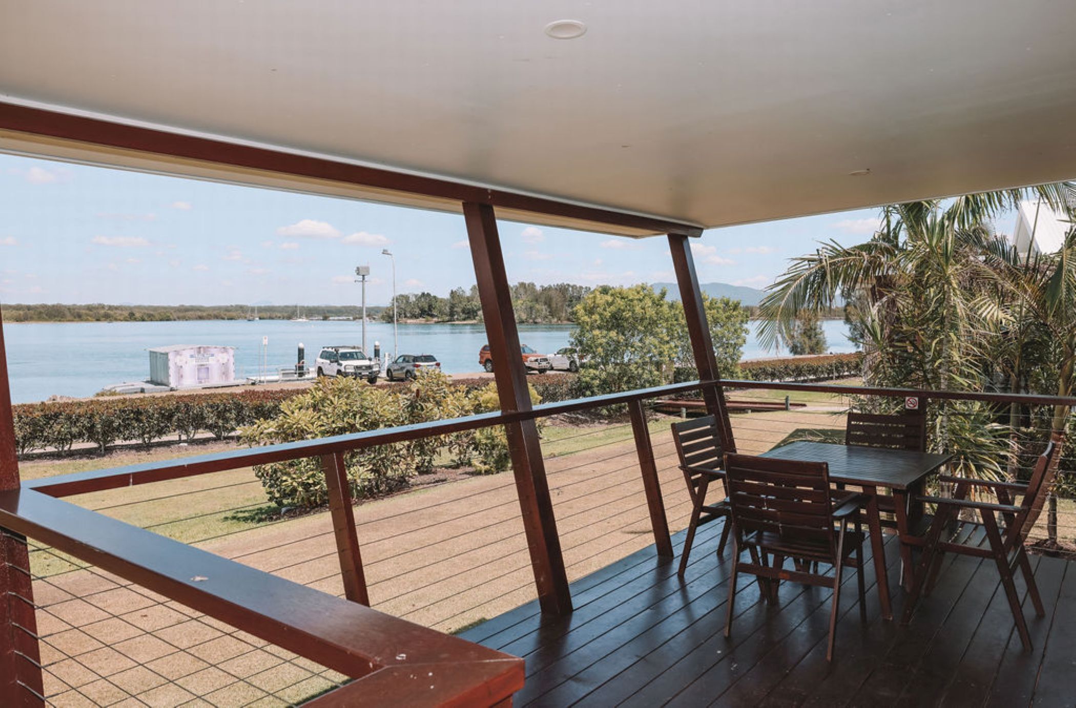 Un balcón con vista a un lago, terraza de madera y zona de estar al aire libre.