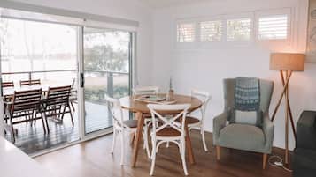 A dining area with a round table and white chairs, a grey armchair, and a floor lamp.