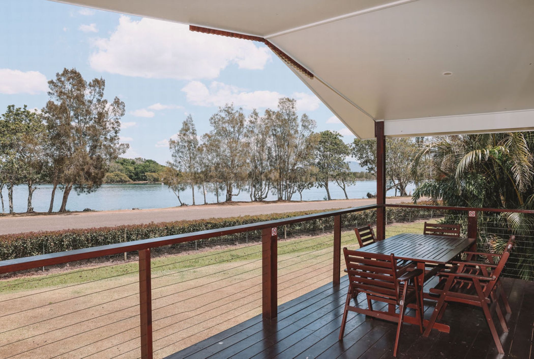 Una terraza de madera con una mesa y sillas que da a un lago.
