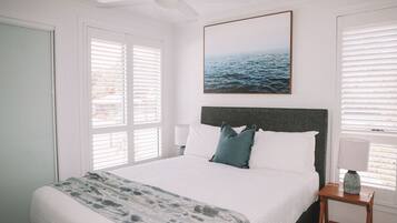 Ein Schlafzimmer mit einem Bett, einem Deckenventilator, einem gerahmten Bild an der Wand und einem Fenster mit Jalousien.