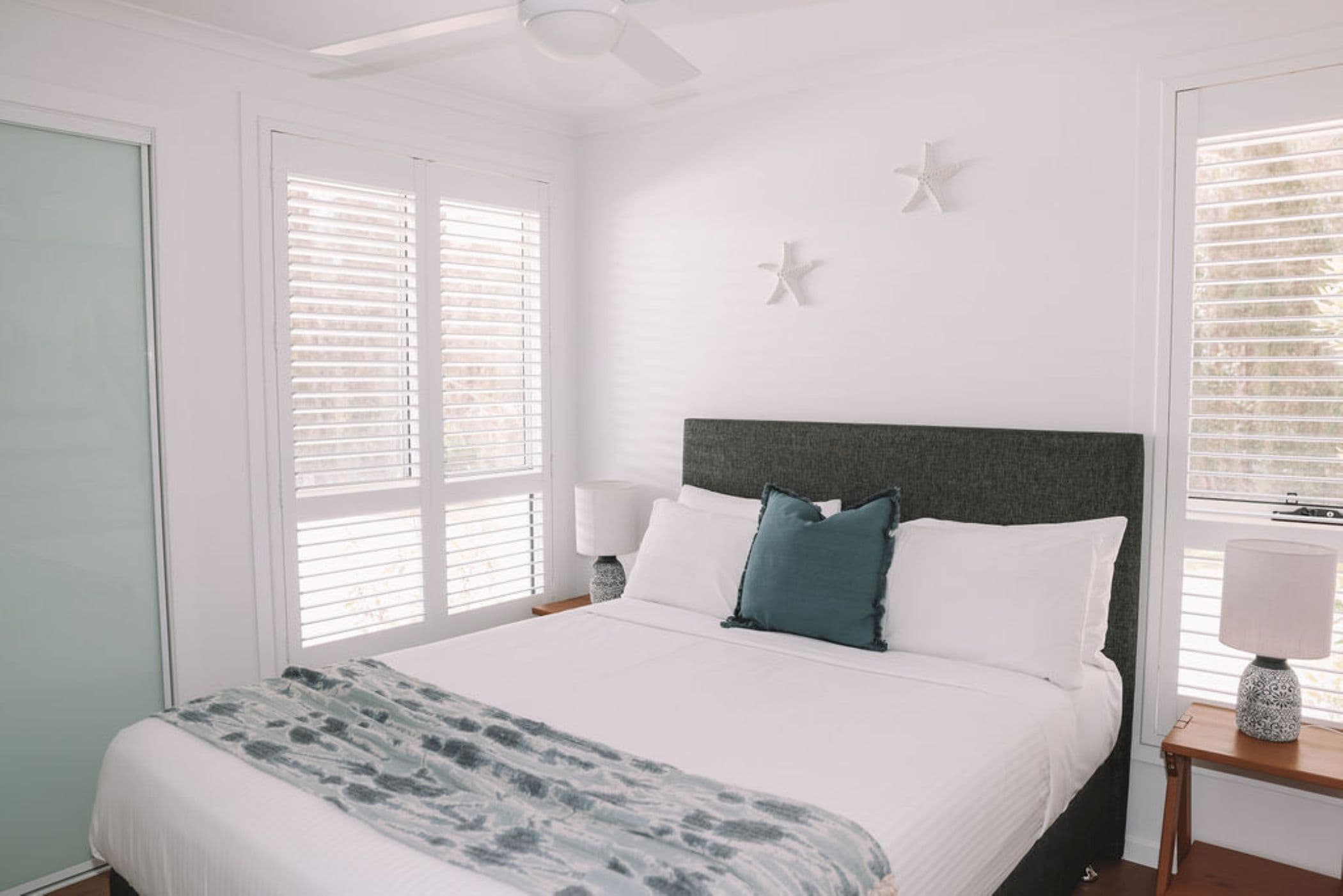 A bedroom with a bed, a nightstand, a lamp, and two star decorations on the wall.