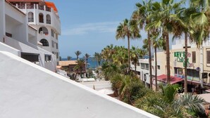 A coastal hotel with a white facade, palm trees, and a view of the sea. - Parque Santiago II 228 - Two Bed (Playa de la Américas)