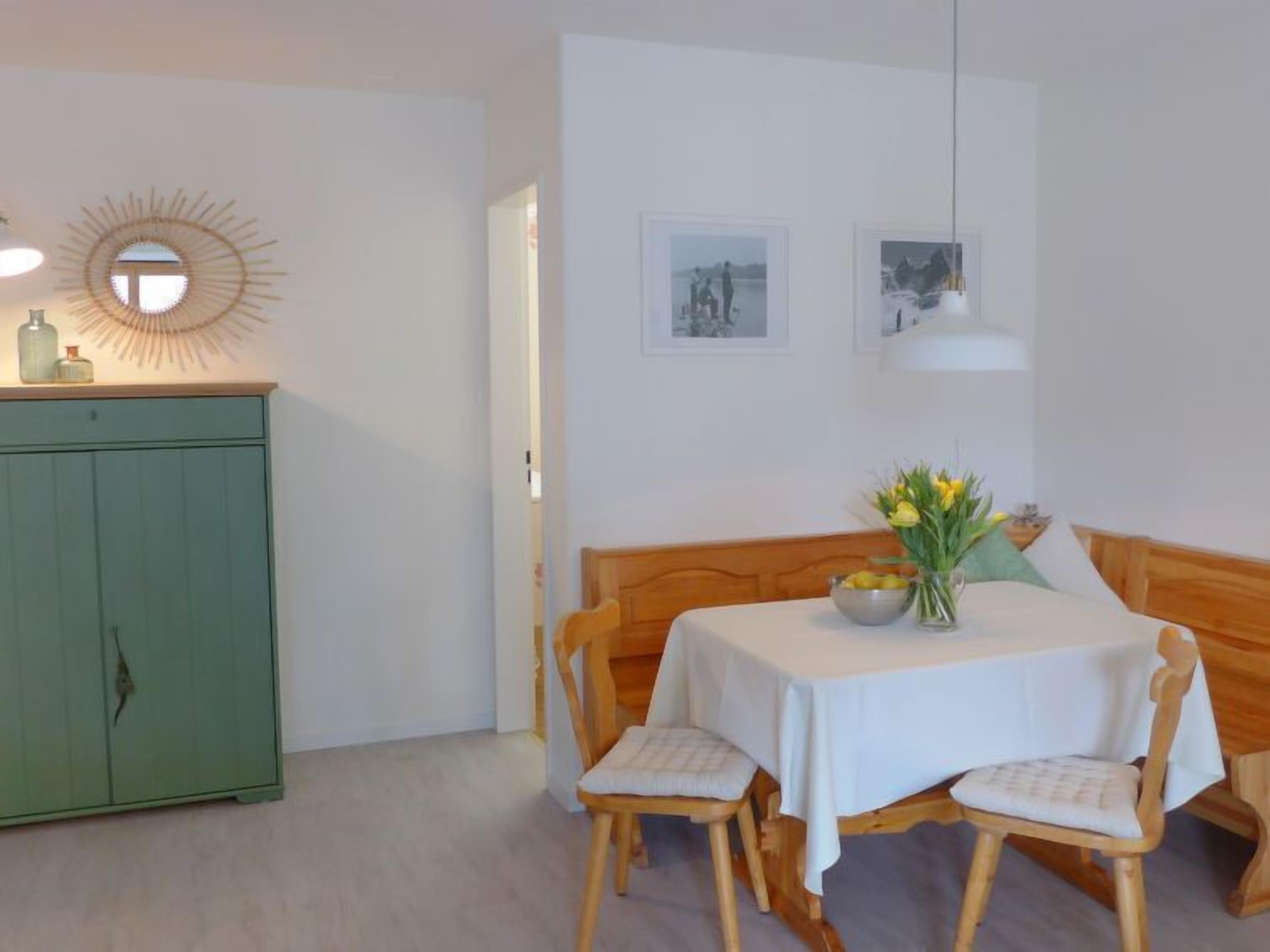 Ein Essbereich mit einem Tisch für zwei Personen, einem grünen Schrank und zwei gerahmten Bildern an der Wand.