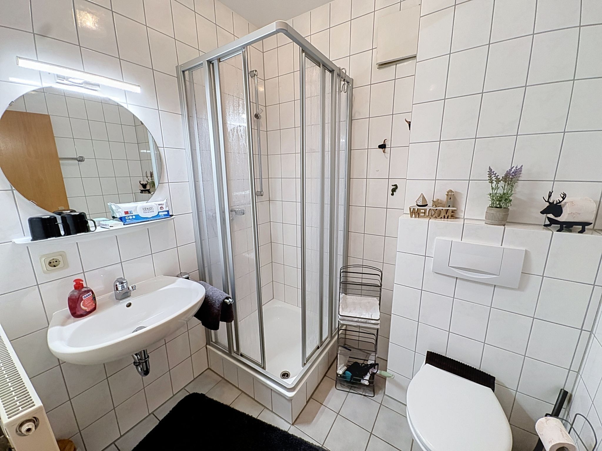 Un baño con ducha, lavabo, inodoro y espejo.