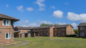 A row of brick apartment buildings with a clear blue sky and a few clouds. - University Campus Park Wood by Interhome (Canterbury)
