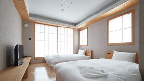 A hotel room with two beds, a wooden desk, and a television. - KAMAKURA Hotel (Kamakura)