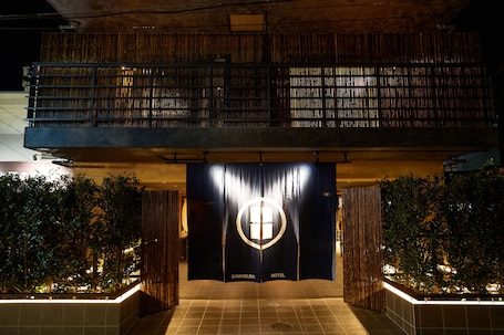 A hotel entrance with a dark facade, a visible logo, and a tiled floor.