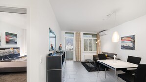 Ein modernes Wohnzimmer mit einer Couch, einem Esstisch und einer Küchenzeile.
