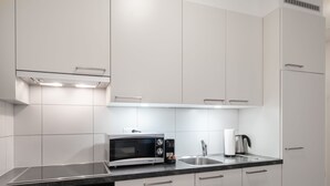 Eine moderne Küche mit weißen Schränken, einem eingebauten Backofen, einer Mikrowelle und einer Spüle aus Edelstahl.