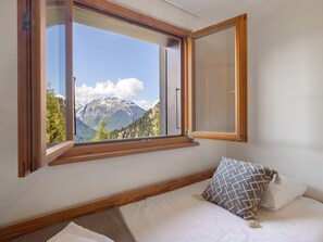 A bedroom with a large window offering a mountain view.