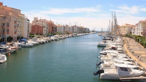 Un puerto deportivo con barcos amarrados a lo largo de un canal, rodeado de edificios de varios pisos.