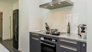 A modern kitchen with a built-in oven, a microwave, and a stainless steel range hood. - Apartment Modern by Interhome (Interlaken)