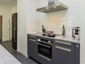 Een moderne keuken met een inbouwoven, een magnetron en een roestvrijstalen afzuigkap.