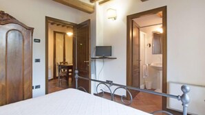 A hotel room with a bed, a TV, a bathroom, and a dining area. - Montecorneo by Interhome (Perugia)
