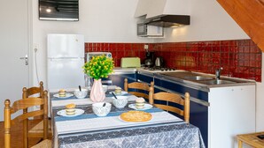 Une cuisine compacte avec un coin repas, comprenant un réfrigérateur, un four à micro-ondes, une cuisinière et un évier.
