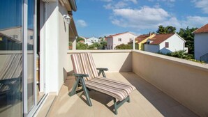 A balcony with a striped chair and a table, overlooking a residential area with houses. - Lastavica by Interhome (Vodice/Jadrija)