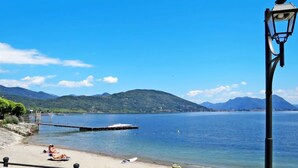 Uma praia com um cais que se estende por águas calmas, rodeada por montanhas.