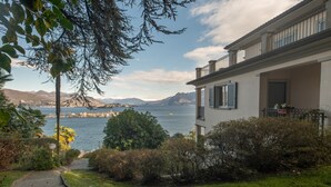 Um imóvel costeiro com um caminho pavimentado que leva a um edifício com varanda com vista para o mar.