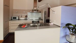 Une cuisine moderne équipée d’un four à micro-ondes, d’une bouilloire et d’un évier.