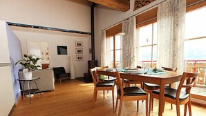 Un coin repas avec une table et des chaises en bois, une petite table d’appoint et une plante.