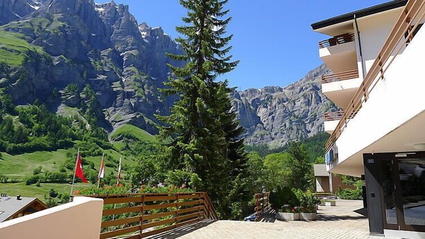 A hotel with a mountain view, a wooden fence, and a flag. - Ringstrasse Apt 423 by Interhome (Leukerbad)