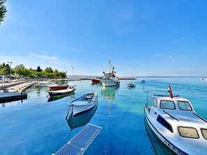 A marina with several boats docked, a pier with a few cars, and a clear blue sky.