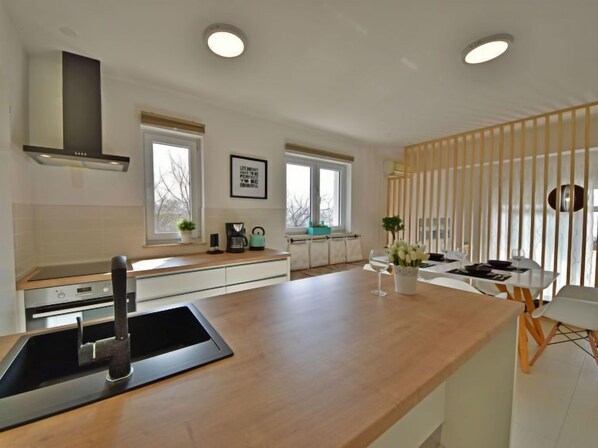 A modern kitchen with a central island, built-in oven, and a large window providing natural light.