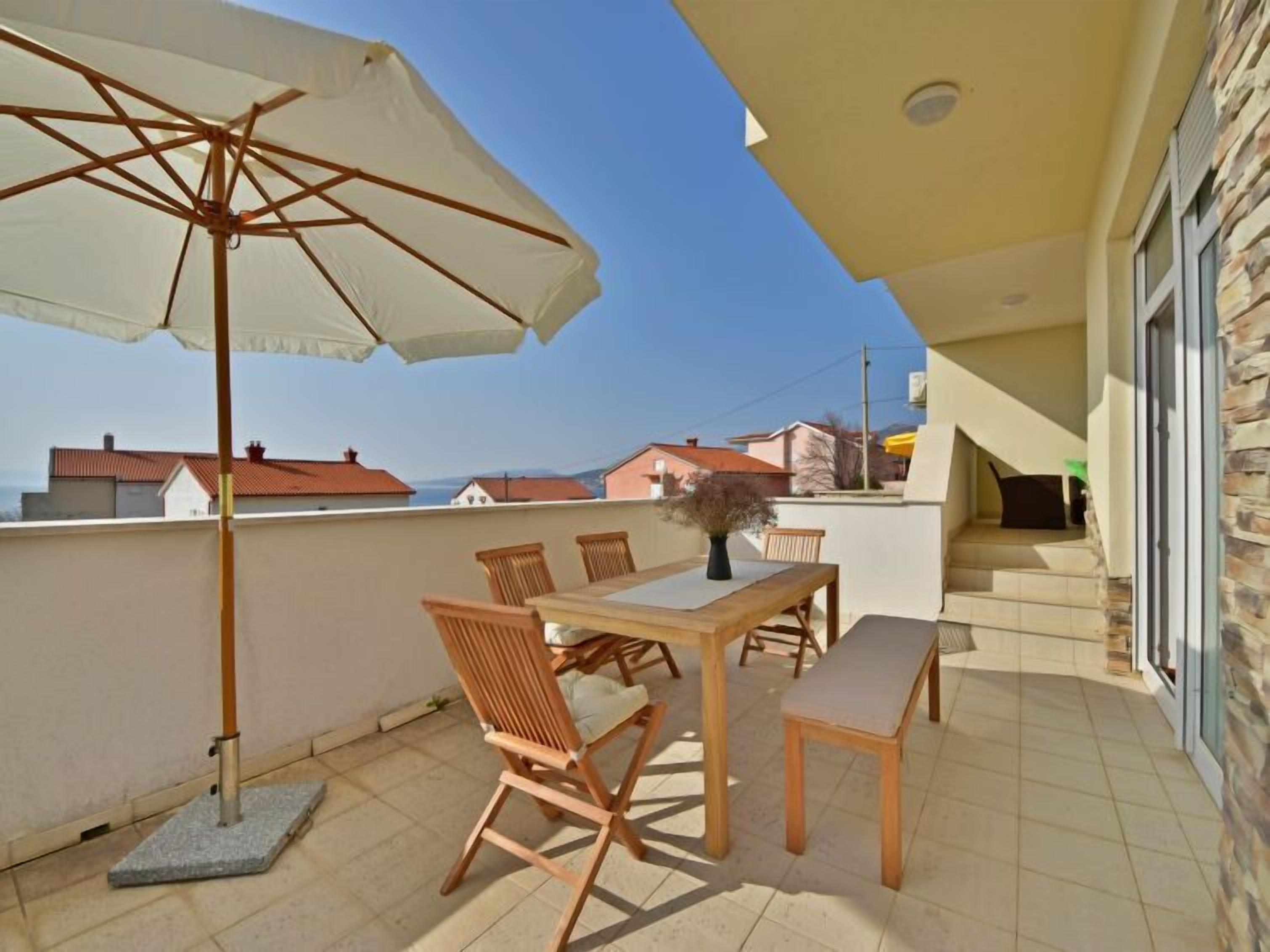 Ein Balkon mit Tisch, Stühlen und Sonnenschirm.