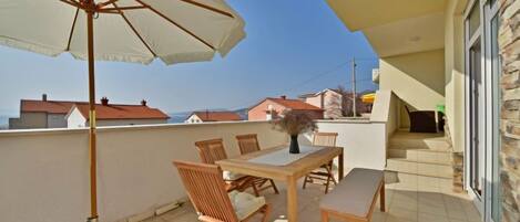 A balcony with a table, chairs, and an umbrella.