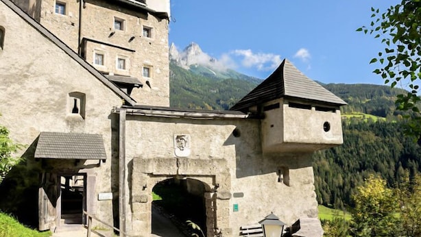 A historic stone building with a steeply pitched roof, a tower, and a large arched entrance. - Edelweiss by Interhome (Werfenweng)