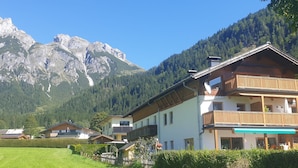 A mountain chalet with a balcony, surrounded by lush greenery and a backdrop of rocky mountains. - Edelweiss by Interhome (Werfenweng)