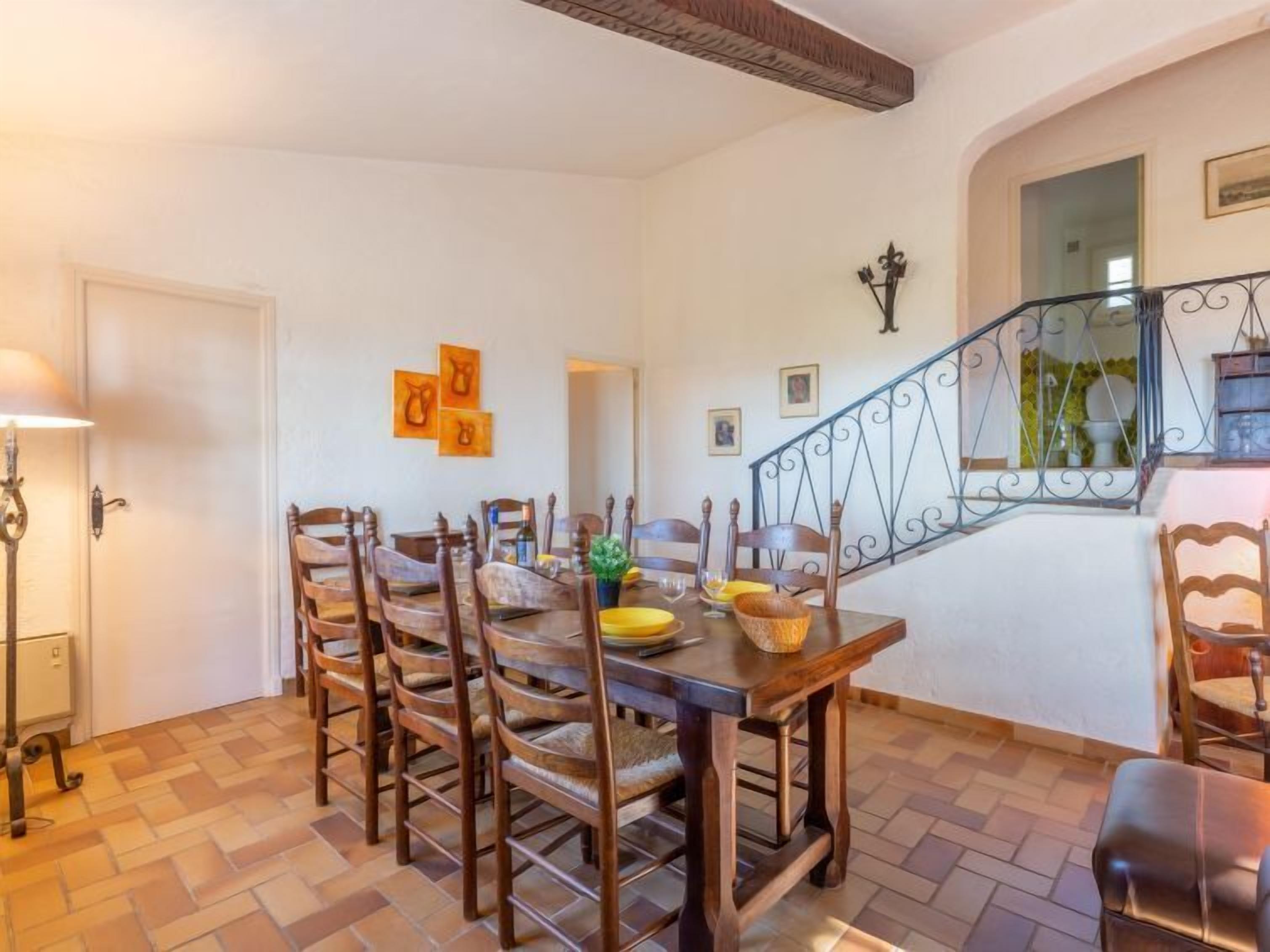 A dining area with a wooden table and chairs, a staircase, and a door.