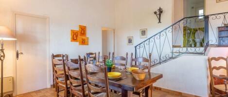 A dining area with a wooden table and chairs, a staircase, and a door.