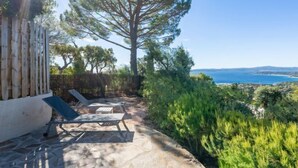 Une terrasse avec deux chaises longues, une clôture en bois et une vue sur la mer.