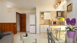 A compact living space with a kitchenette, a dining area with a glass table, and a sofa. - Playsol by Interhome (Calpe/Calp)