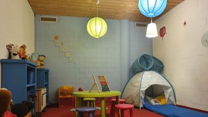 A playroom with a red carpet, a blue playpen, a green table with an abacus, and a wooden bench with stuffed animals. - Chalet Abendrot apARTments by Interhome (Grindelwald)