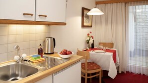 A compact kitchen with a sink, kettle, and a dining area with a table set for two. - Chalet Abendrot apARTments by Interhome (Grindelwald)
