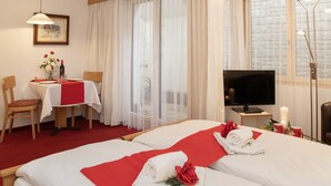 A hotel room with a bed, a TV, a desk with a chair, and a window with curtains. - Chalet Abendrot apARTments by Interhome (Grindelwald)