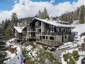A modern multi-story building with balconies, surrounded by snow-covered trees and a mountainous backdrop. - Arsets 203/12 by Interhome (Alpe des Chaux)