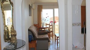 Un salon comprenant un canapé, une table à manger avec des chaises, une table basse en verre et un miroir décoratif.