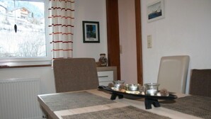 A dining area with a table set for two, a radiator, a window with curtains, and a framed picture on the wall. - Kaufmann by Interhome (Pians)