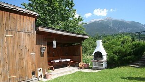 A rustic wooden building with a covered outdoor seating area and a stone oven. - Kaufmann by Interhome (Pians)