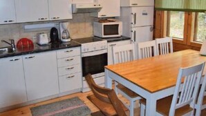 Une cuisine compacte avec des meubles blancs, une table en bois et une fenêtre donnant sur un beau paysage.
