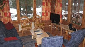 Un salon confortable avec un canapé, deux fauteuils, une table basse, un téléviseur et une fenêtre avec des rideaux.