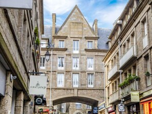 Ein historisches Steinhaus mit einem zentralen Bogenportal, zahlreichen Fenstern und Balkonen.