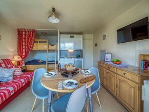 Un espacio habitable compacto con kitchenette, comedor y zona de descanso.