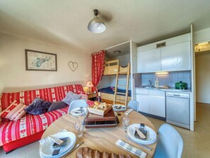 A compact living space with a kitchenette, a dining area, and a bunk bed.