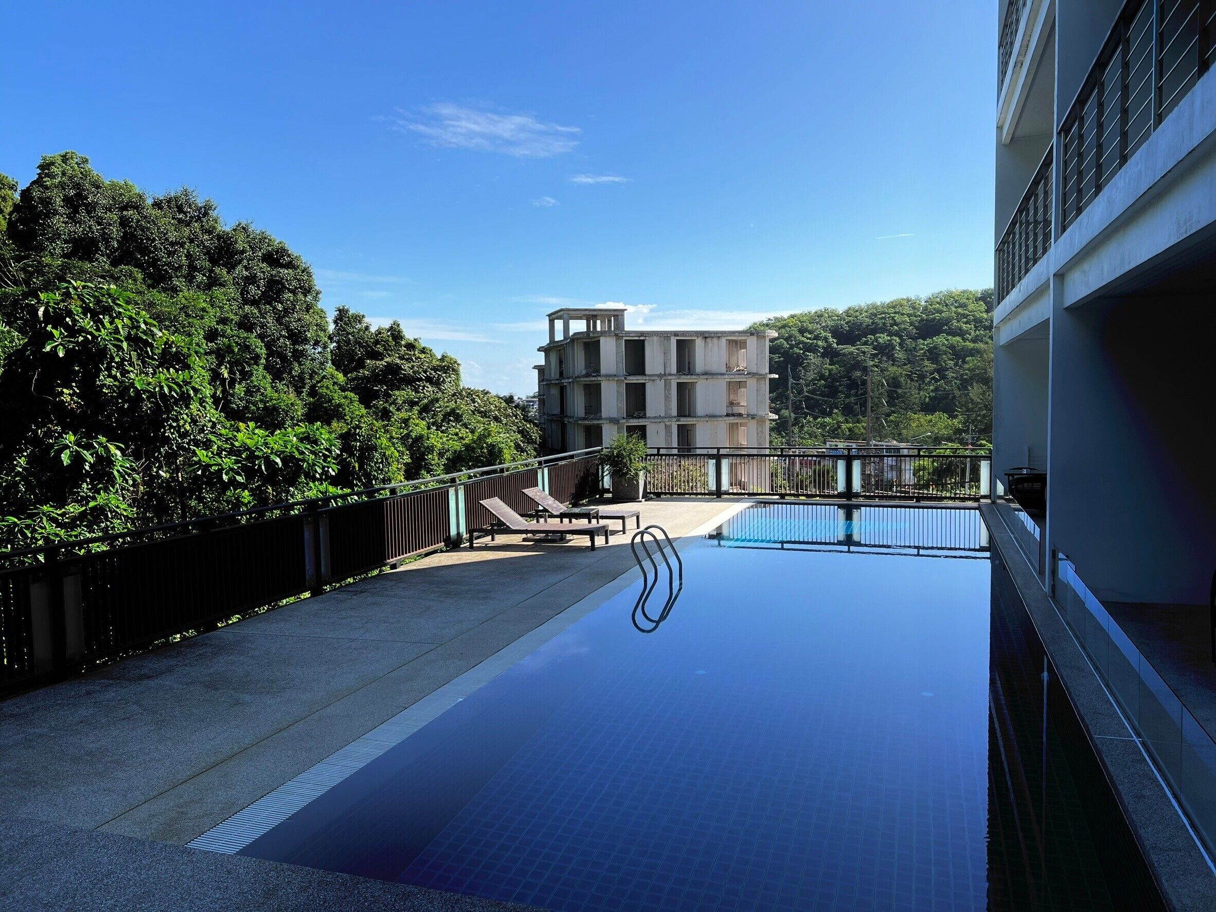 A swimming pool with a view of a building and trees.